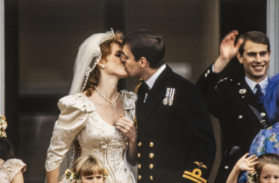 View of just-married couple Sarah, Duchess of York and Prince Andrew, Duke of York as they kiss on the balcony of Buckingham Palace, London, England, July 23, 1986. Also visible is Andrew's brother, Prince Edward, Earl of Wessex as he waves. (Photo by Derek Hudson/Getty Images)