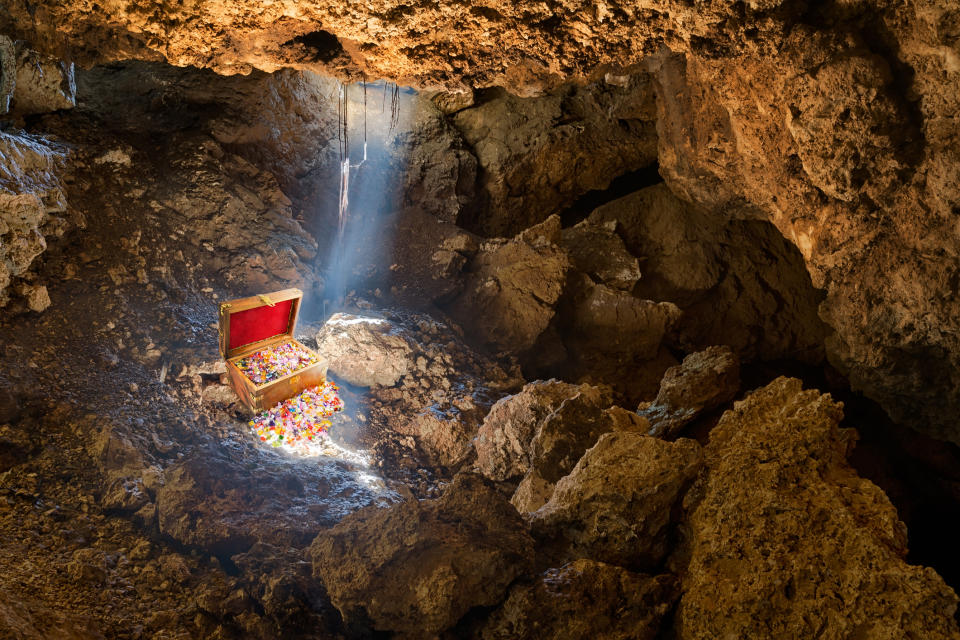 Cave with skylight streaming sunlight on a treasure chest.