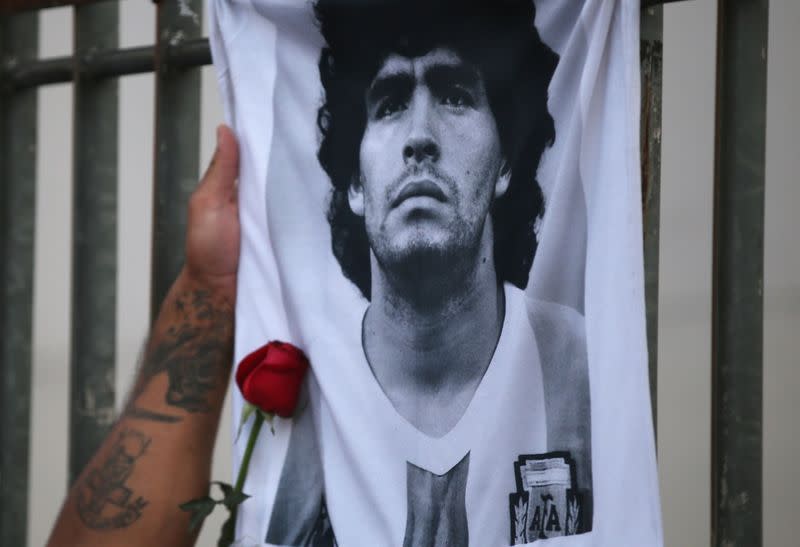 A rose is placed next to a banner of Argentine soccer great Diego Maradona as fans gather to mourn his death, at the Obelisk of Buenos Aires