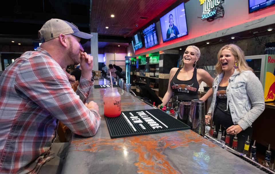 From left, Mo Roberts has a laugh with bartenders Brittaney Kirk and Ciara Wingard at the new Wild Greg's Saloon restaurant in downtown Pensacola on Friday, Feb. 9. 2024.