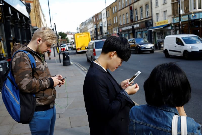Pedestrians look at their phones near Brick Lane in London. REUTERS/Stefan Wermuth