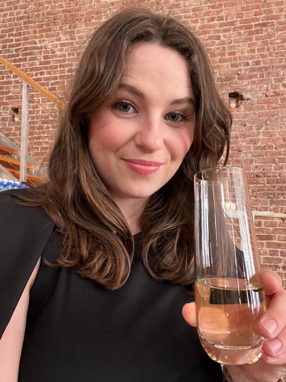 A woman holds up a glass of champagne in a selfie.