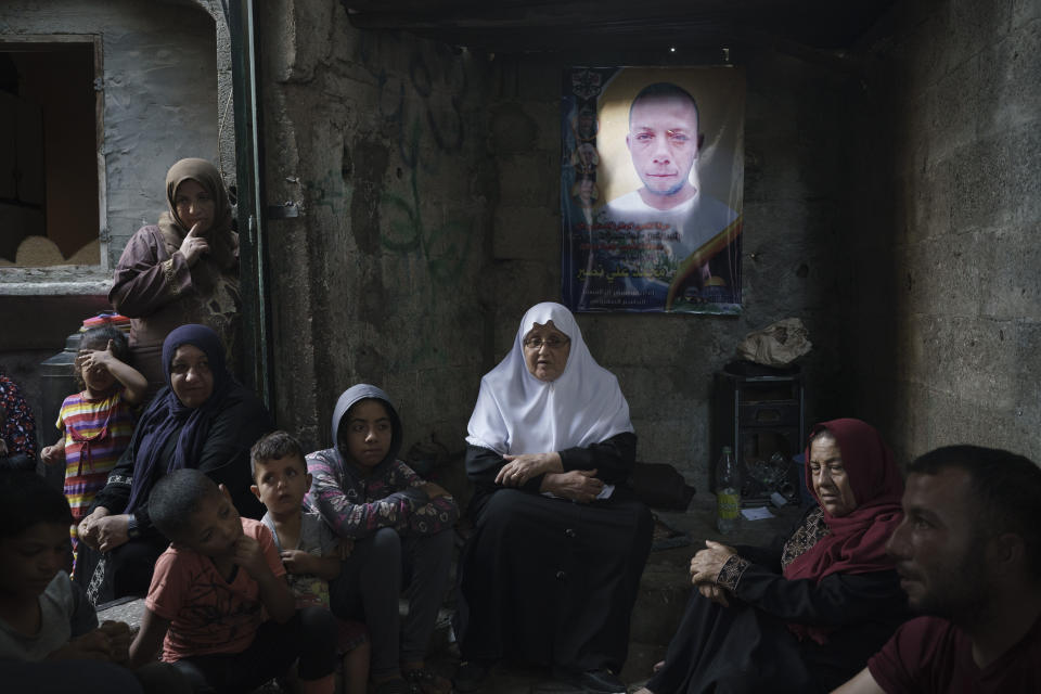 Members of the Nassir family sit under a poster of Mohamed Nassir, who died in the recent 11-day war between Israel and Hamas, the militant group that controls Gaza, Saturday, June 12, 2021 in Beit Hanoun, northern Gaza. (AP Photo/Felipe Dana)