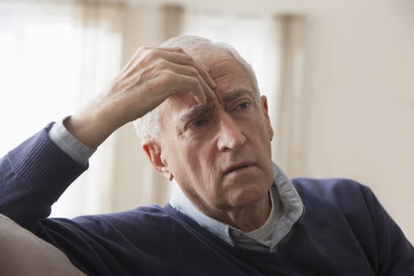 A worried elderly man with his hand on her forehead.