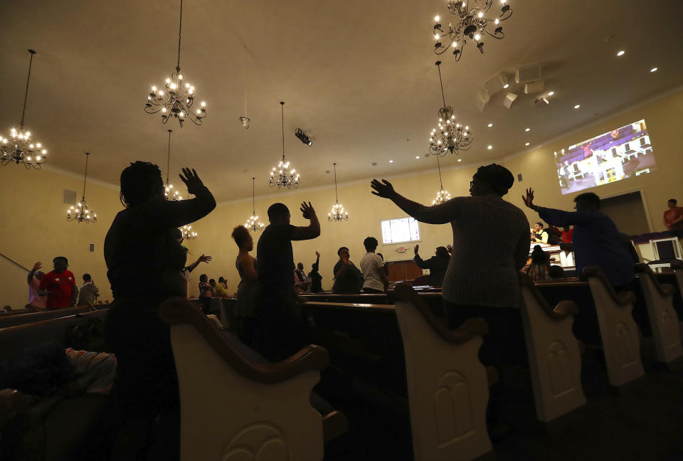 At the end of worship service, members wave goodbye to each other rather than hug or shake hands while as they practice social distancing in the pews at the Union Springs Baptist Church on Sunday, March 29, 2020, in Rutledge, Ga. Pastor Robert L. Terrell spoke to the congregation on how to worship while keeping social distance and two nurses met worshipers as they entered the church taking temperatures to keep the congregation healthy. (Curtis Compton/Atlanta Journal-Constitution via AP)