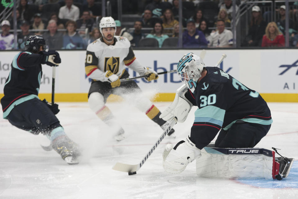 Seattle Kraken goaltender Martin Jones protects the puck as Vegas Golden Knights center Chandler Stephenson approaches while Seattle Kraken center Yanni Gourde defends during the first period of an NHL hockey game, Saturday, Oct. 15, 2022, in Seattle. (AP Photo/Jason Redmond)