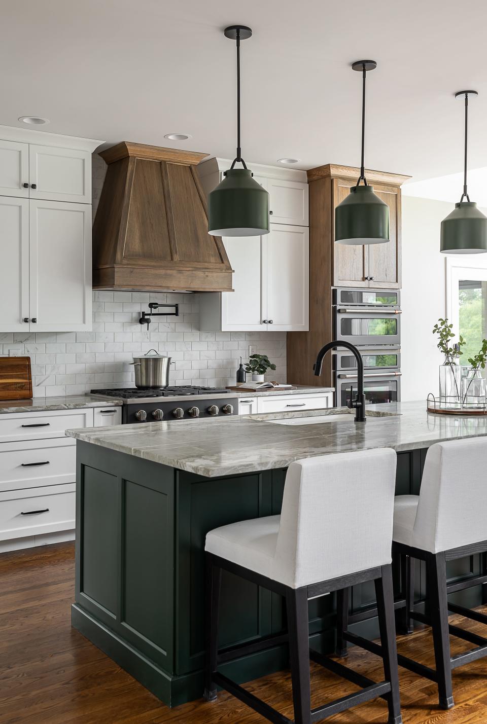 The hunter-green base of this kitchen island matches the pendant lights that hang above in this renovated kitchen in Louisville.