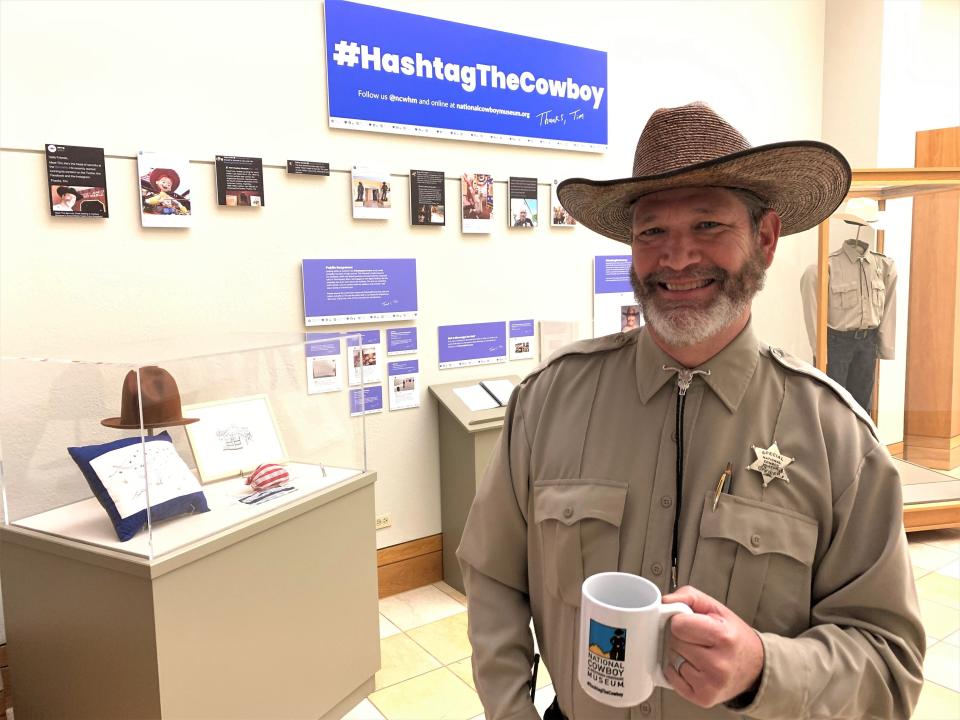 Tim Tiller took over the the National Cowboy & Western Heritage Museum's social media during the shutdown and became an internet sensation. Here's he's pictured with his coffee mug and fan gifts at the "#HastagTheCowboy" exhibit in Oklahoma City.