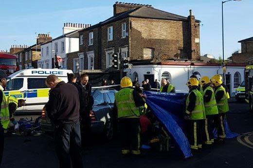 Crash scene: Fire crews erected blue tarpaulin while paramedics treated the biker: @HackneyMPS