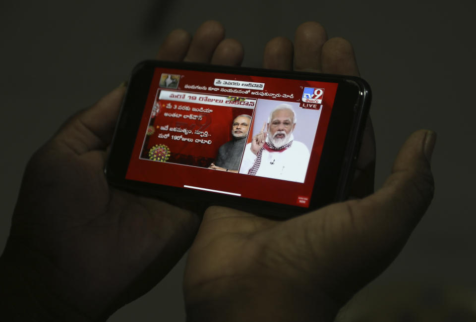 A man in Hyderabad, India watches on his mobile phone Prime Minister Narendra Modi address the nation in a televised speech about COVID-19 situation, Tuesday, April 14, 2020. Modi has extended the world’s largest coronavirus lockdown hoping to head off the epidemic's peak as officials race to make up for lost time. (AP Photo/Mahesh Kumar A)