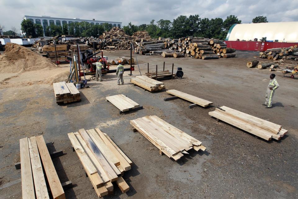 In this Wednesday, Aug. 15, 2012 photo, workers use a large saw to cut discarded tree trunks into railroad ties at Citilog in Newark, N.J. The Newark company takes unwanted trees from the so-called urban forest — parks, yards, streets and wherever else a tree might grow in a city — and turns them into furniture, flooring and other materials. (AP Photo/Mel Evans)