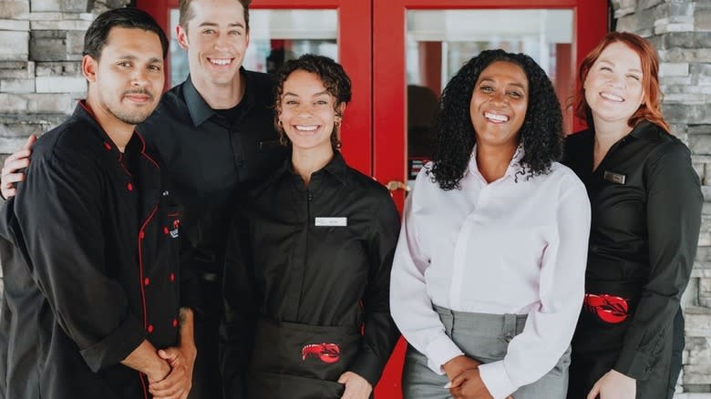 Smiling restaurant employees in front of red door