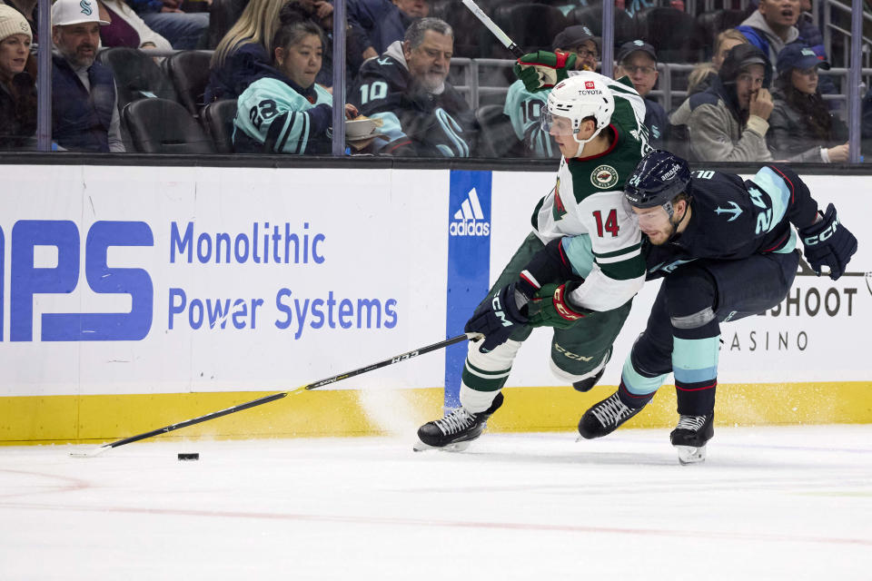 Minnesota Wild center Joel Eriksson Ek (14) battles with Seattle Kraken defenseman Jamie Oleksiak (24) for the puck during the second period of an NHL hockey game, Sunday, Dec. 10, 2023, in Seattle. (AP Photo/John Froschauer)