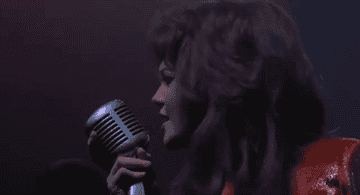 Diane Lane sings into a microphone