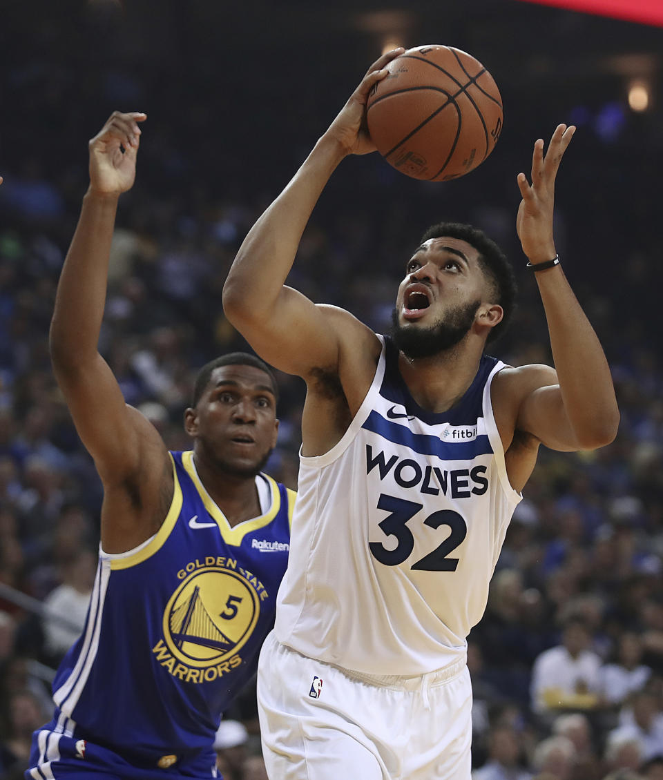 Minnesota Timberwolves' Karl-Anthony Towns, right, looks for a shot next to Golden State Warriors' Kevon Looney (5) during the first half of an NBA basketball game Friday, Nov. 2, 2018, in Oakland, Calif. (AP Photo/Ben Margot)