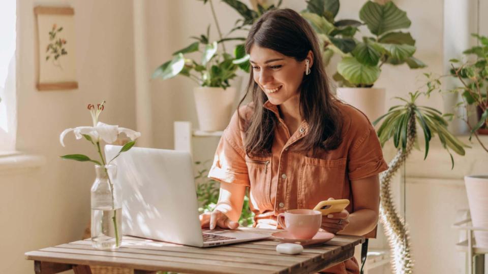 Young woman at home doing research on her laptop and smiling