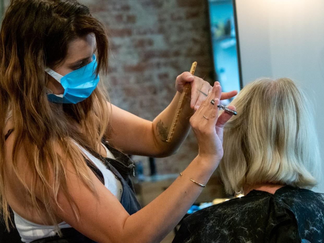 beauty salon hair stylist coronavirus A cosmetologist styles a customers hair at Parlour Salon as beauty salons, barber shops and spas begin to reopen in the wake of the Coronavirus COVID-19 pandemic, Wednesday, May 20, 2020, in Cincinnati, Ohio, United States. (Photo by Jason Whitman/NurPhoto via Getty Images)