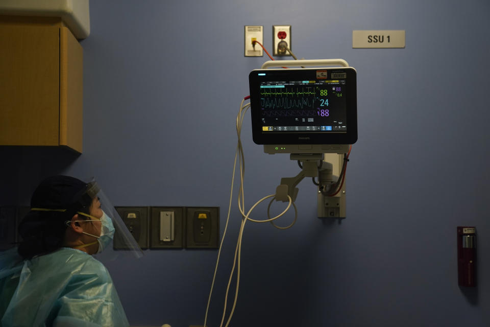 Registered nurse Keran Li looks at a monitor while checking on her patient in a COVID-19 unit at St. Joseph Hospital in Orange, Calif. Thursday, Jan. 7, 2021. California health authorities reported Thursday a record two-day total of 1,042 coronavirus deaths as many hospitals strain under unprecedented caseloads. (AP Photo/Jae C. Hong)