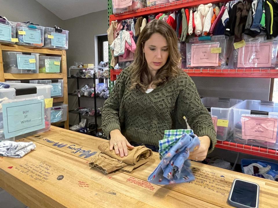 Tess Frear, executive director of Helping Mamas Knoxville, inspects clothes to see that they are new or gently used. Dec. 27, 2022