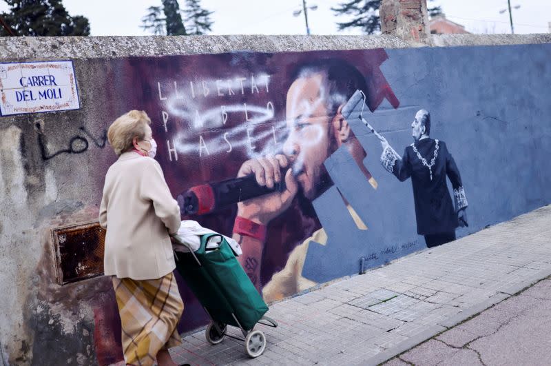 A woman walks past a graffiti by Catalan artist Cinta Vidal in Cardedeu