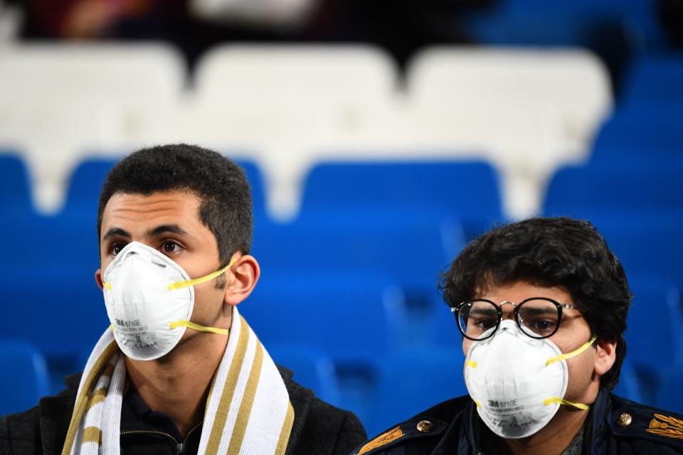 Football fans wearing masks in light of the coronavirus outbreak wait for the start of the Spanish League football match between Real Madrid and Barcelona at the Santiago Bernabeu stadium in Madrid on March 1, 2020. (Photo by GABRIEL BOUYS / AFP) (Photo by GABRIEL BOUYS/AFP via Getty Images)