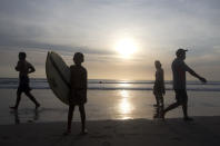 People walk on beach during a sunset at Kuta beach, Bali, Indonesia on Thursday, Oct. 14, 2021. The Indonesian resort island of Bali welcomed international travelers to its shops and white-sand beaches for the first time in more than a year Thursday - if they're vaccinated, test negative, hail from certain countries, quarantine and heed restrictions in public. (AP Photo/Firdia Lisnawati)