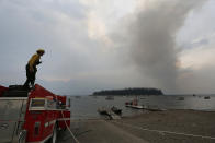 <p>A firefighter refills a water truck at Leek’s Marina on the shore of Jackson Lake, just south of a wildfire, which is visible in the background, in north Grand Teton National Park, Wyo., Aug 24, 2016. (AP Photo/Brennan Linsley) </p>