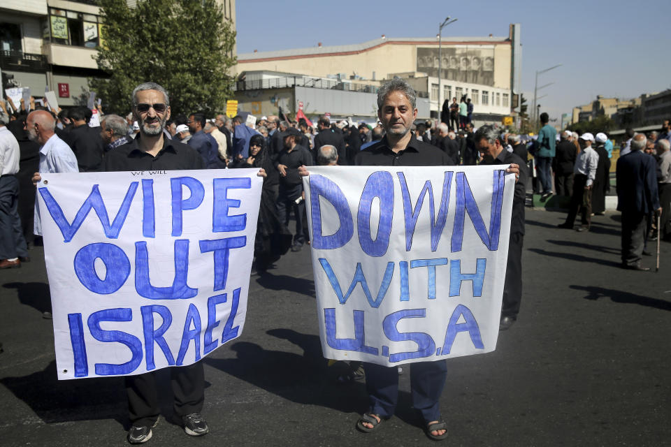 Two Iranian worshippers hold up anti-American and anti-Israeli placards, in a rally to condemn Saturday's terror attack in Ahvaz, after Friday prayers in Tehran, Iran, Friday, Sept. 28, 2018. On Saturday, armed men disguised as soldiers killed 24 and wounded 60 people in an attack targeting a military parade in Ahvaz, southern Iran. (AP Photo/Ebrahim Noroozi)