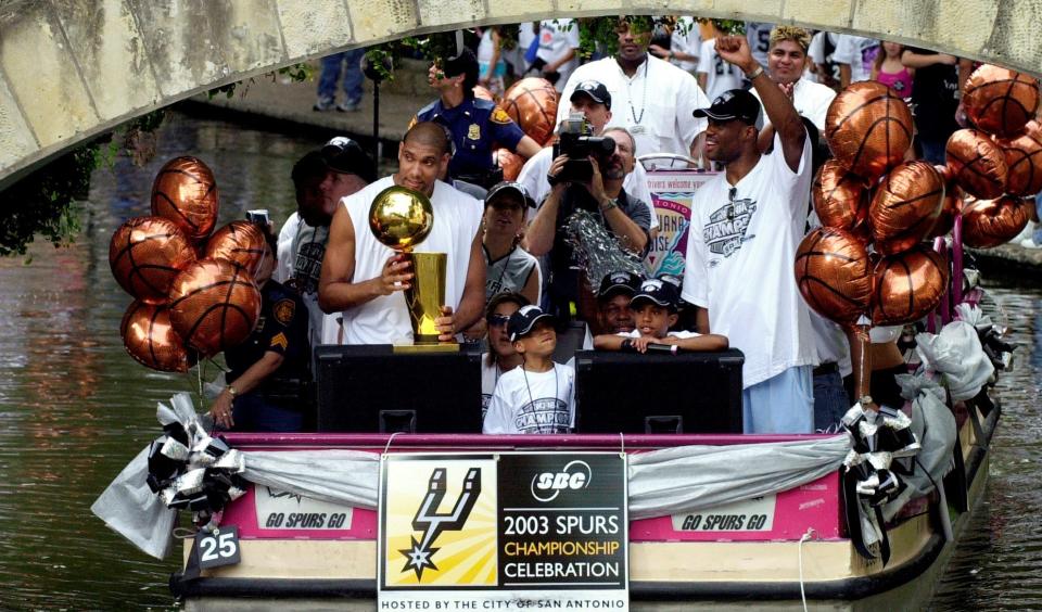 San Antonio Spurs forward Tim Duncan, left, and center David Robinson, right, respond to the crowd as they ride a barge during a  parade to celebrate their NBA championship win, along the San Antonio River in downtown San Antonio.