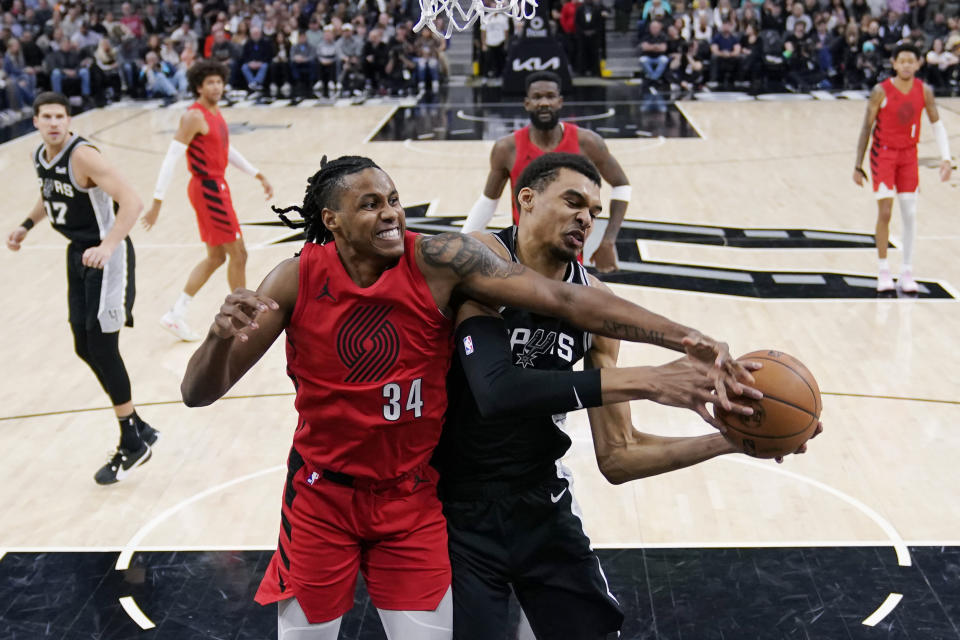 Portland Trail Blazers forward Jabari Walker (34) and San Antonio Spurs center Victor Wembanyama (1) vie for control of a rebound during the first half of an NBA basketball game in San Antonio, Friday, Jan. 26, 2024. (AP Photo/Eric Gay)