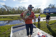 J.C. Derison, a DeSoto County commissioner, who is using his airboat along with other citizen volunteers, carries an oxygen tank as he evacuates residents during flooding along the Peace River in the aftermath of Hurricane Ian in Arcadia, Fla., Monday, Oct. 3, 2022. (AP Photo/Gerald Herbert)