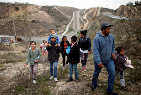 FILE PHOTO: Migrants from Honduras, part of a caravan of thousands from Central America trying to reach the United States, walk next to the border fence as they prepare to cross it illegally, in Tijuana, Mexico, December 14, 2018. REUTERS/Mohammed Salem/File Photo