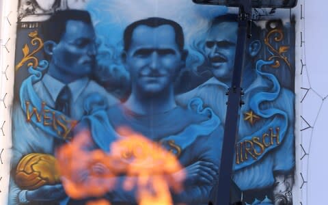 Artist Solomon Souza paints the Holocaust Commemorative Mural at Stamford Bridge as a flame flicker - Credit: Getty Images