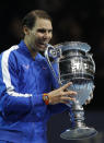 Spain's Rafael Nadal bits the ATP World Number 1 trophy as he poses for photographs following the presentation on court after his match against Stefanos Tsitsipas of Greece at the ATP World Tours Finals in the O2 Arena in London, Friday, Nov. 15, 2019. (AP Photo/Alastair Grant)