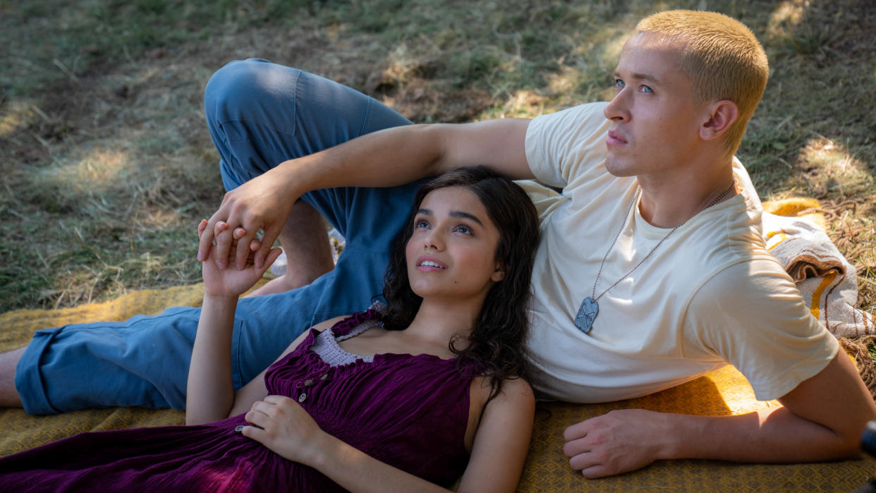  First image from The Hunger Games: The Ballad of Songbirds and Snakes featuring Lucy Gray Baird (Rachel Zegler) and Coriolanus Snow (Tom Blyth) lying together on a blanket in some woods. 