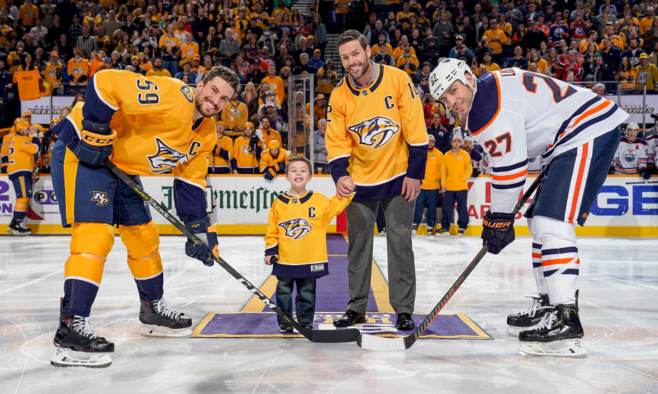 NASHVILLE, TN - FEBRUARY 25: Former Nashville Predator Mike Fisher and his son Isaiah drop the puck between Roman Josi #59 and Milan Lucic #27 of the Edmonton Oilers at Bridgestone Arena on February 25, 2019 in Nashville, Tennessee. (Photo by John Russell/NHLI via Getty Images)