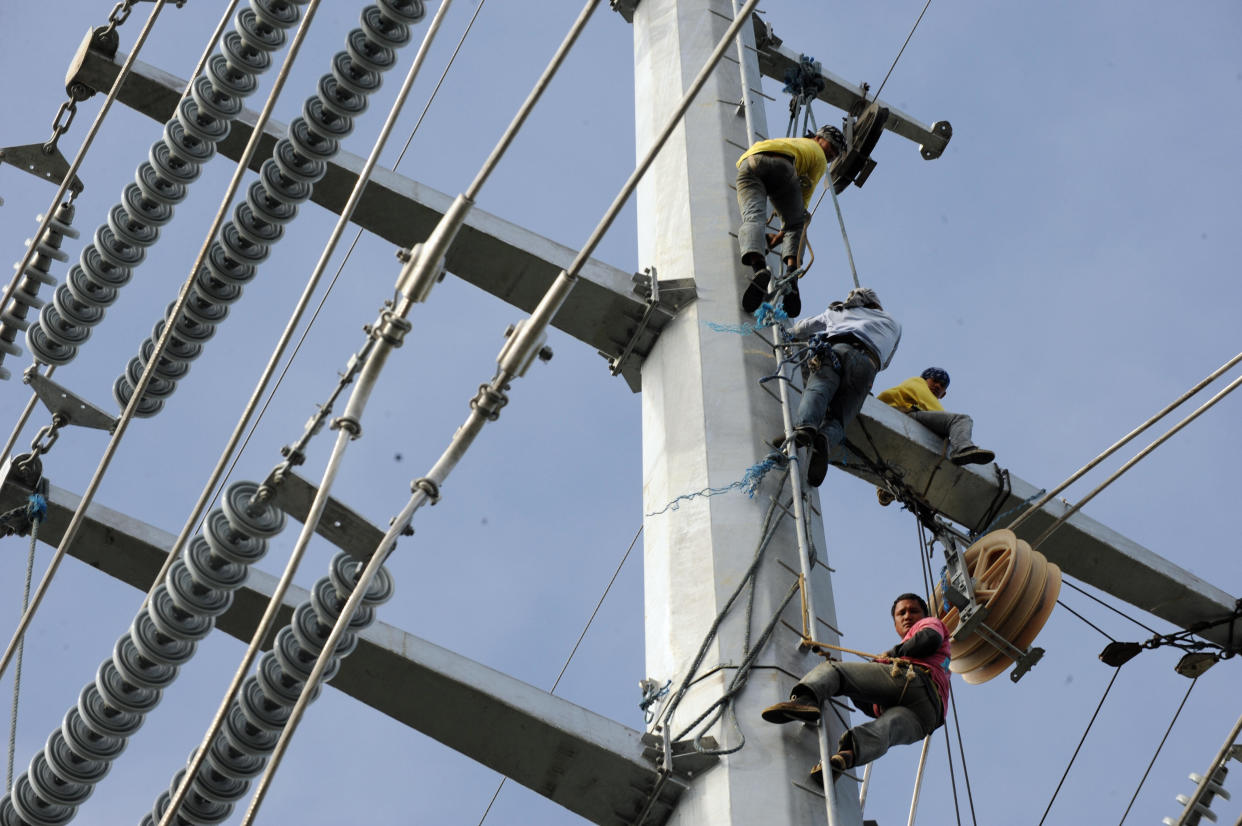 File Photo: Linemen install cables on the Transco power transmission line in Santa Rosa town south of Manila on January 15, 2009 as the Chinese-led consortium officially took over a 25-year concession of the Philippines' national electricity grid as part of the government's privatization program. (Photo: ROMEO GACAD/AFP via Getty Images)