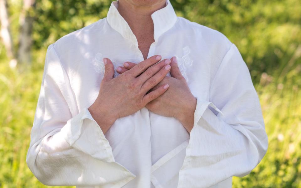 Women's hands on heart in meditating