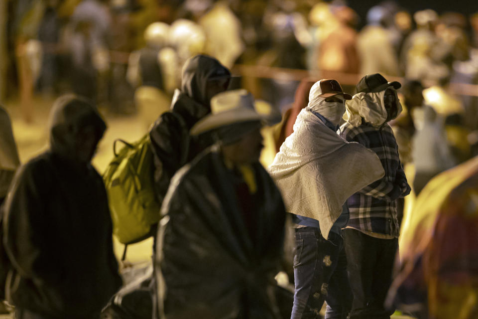 Migrants wait in the cold at a gate in the border fence after crossing from Ciudad Juarez, Mexico into El Paso, Texas, in the early hours of Thursday, May 11, 2023. Migrants rushed across the border hours before pandemic-related asylum restrictions were to expire Thursday, fearing that new policies would make it far more difficult to gain entry into the United States. (AP Photo/Andres Leighton)