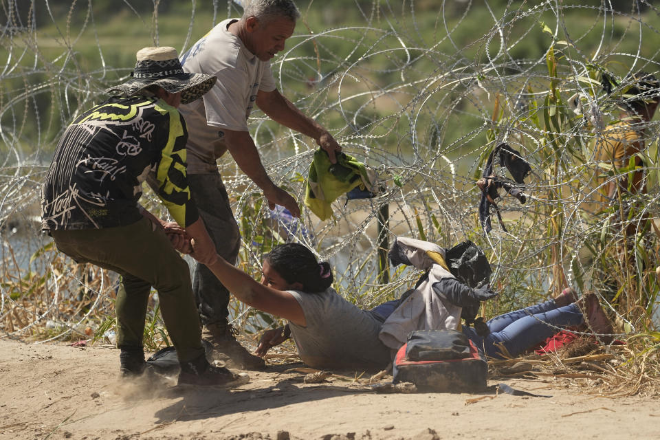 A migrant who crossed into the U.S. from Mexico is pulled under concertina wire along the Rio Grande river, Thursday, Sept. 21, 2023, in Eagle Pass, Texas. (AP Photo/Eric Gay)