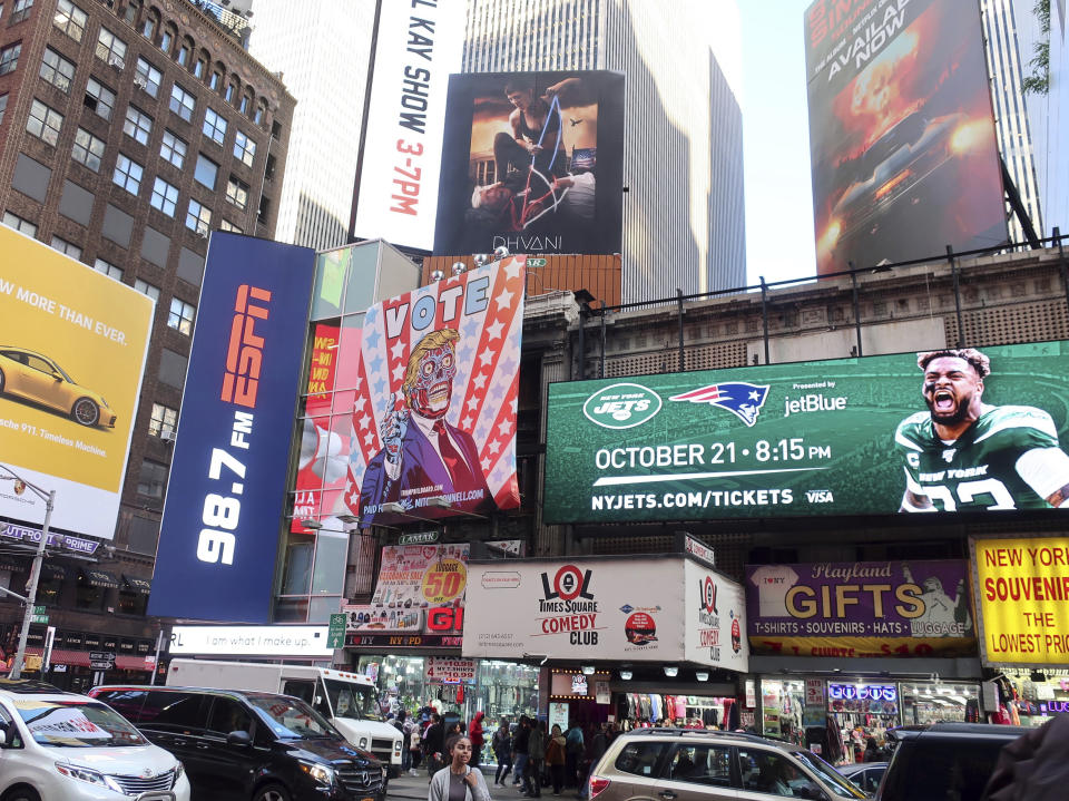 A billboard in New York City's Time Square depicts President Donald Trump being hogtied by a woman clad in athletic wear on Friday, October 18, 2019. The The 30-foot-high billboard is part of an advertising campaign by Dhvani, a Portland-based clothing company. CEO of Dhvani Avi Brown told The Associated Press the billboard was intended to be a comment on the Trump administration's changes to the Title X family planning program blocking federal funding for health providers who refer patients for abortions. (AP Photo/Ted Shaffrey)