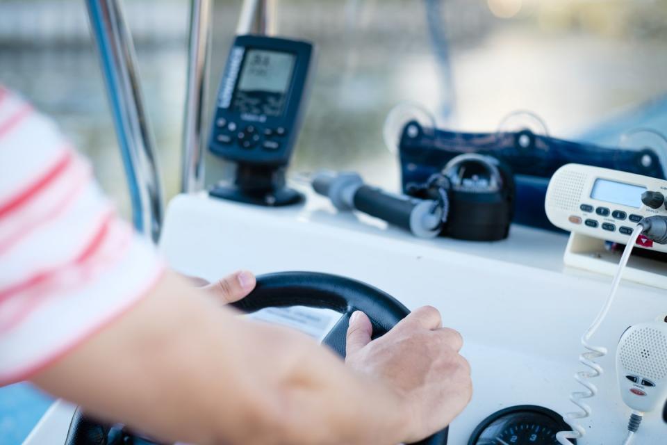 hands at the steering wheel of a fishing boat with fish finder, gps , compass and vhf radio