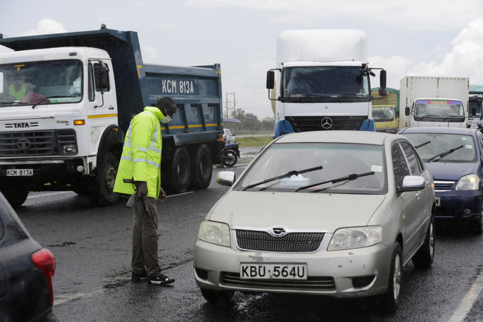 A Kenyan police officer at a road block along Mombasa Road stops vehicles traveling to Mombasa and Machakos, in Nairobi, Kenya, Tuesday, April 7, 2020. Kenya increased its restrictions to combat the coronavirus, announcing travel bans into and out of the capital city, Nairobi, the port of Mombasa and two counties. More than half of Africa’s 54 countries have imposed lockdowns, curfews, travel bans or other restrictions to try to contain the spread of COVID-19. (AP Photo/Khalil Senosi)