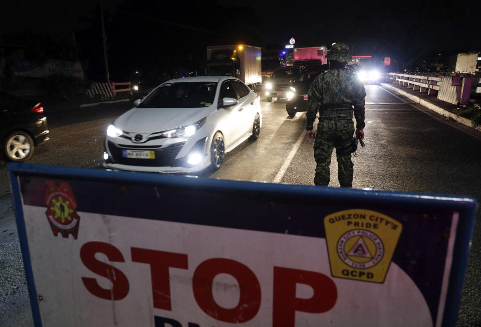 A policeman stands at a checkpoint in Quezon city, metropolitan Manila, Philippines early Sunday March 15, 2020. Thousands of Philippine police, backed by the army and coast guard, have started sealing the densely populated capital from most domestic travelers in one of Southeast Asia's most drastic containment moves against the coronavirus. For most people, the new coronavirus causes only mild or moderate symptoms. For some, it can cause more severe illness, especially in older adults and people with existing health problems. (AP Photo/Aaron Favila)