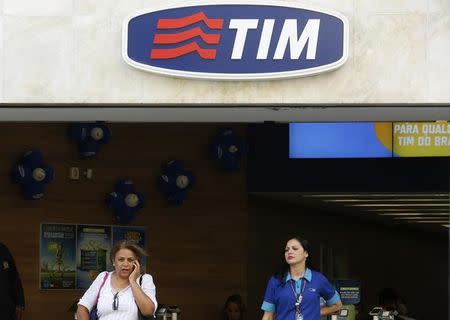 A woman speaks on a mobile phone next to an attendant at a Telecom Italia Mobile (TIM) store in downtown Rio de Janeiro August 20, 2014.