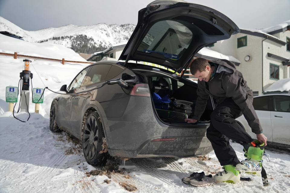 Denver resident Kurt Zanca removes ski boots at his electric vehicle at Arapahoe Basin Thursday, Jan. 19, 2023, in Dillon, Colo. Zanca said he thinks charging infrastructure at ski areas can help encourage hesitant shoppers to purchase an electric vehicle. (AP Photo/Brittany Peterson)