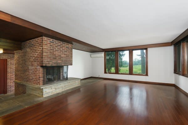 The main living room is anchored by a central brick fireplace, while large picture windows ensure an abundance of natural light is swept inside.