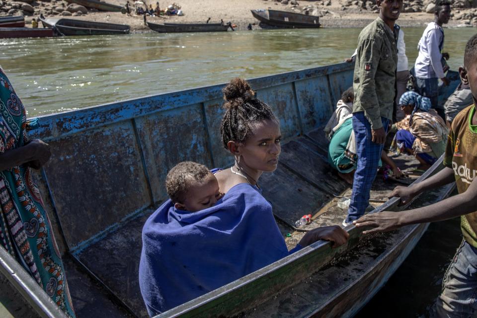 A woman who fled the conflict in the Ethiopia's Tigray waits to go back to Ethiopia with her baby on the banks of the Tekeze River on the Sudan-Ethiopia border, in Hamdayet, eastern Sudan, Tuesday, Dec. 1, 2020. (AP Photo/Nariman El-Mofty)