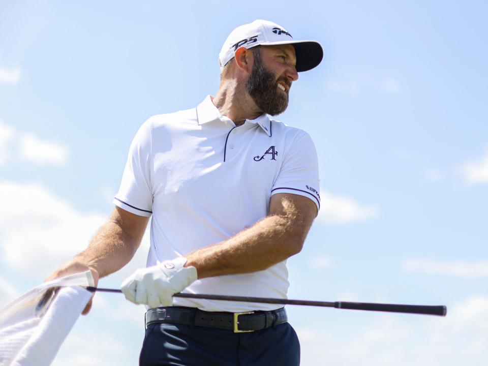 Dustin Johnson of 4Aces GC cleans his golf club on the driving range during the second round of LIV Golf Orlando.