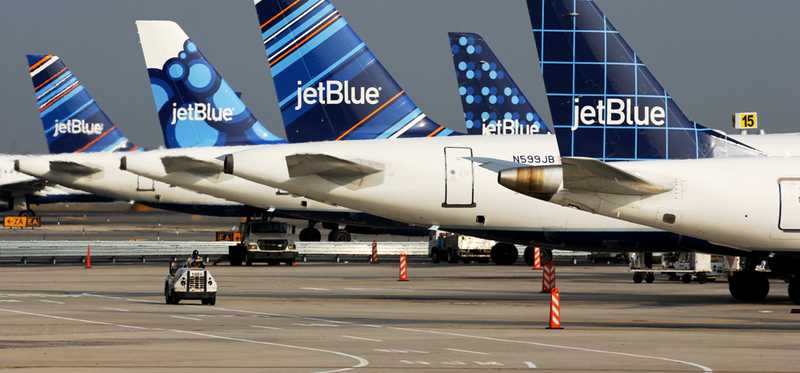 Fleet of JetBlue airplanes at airport gates.